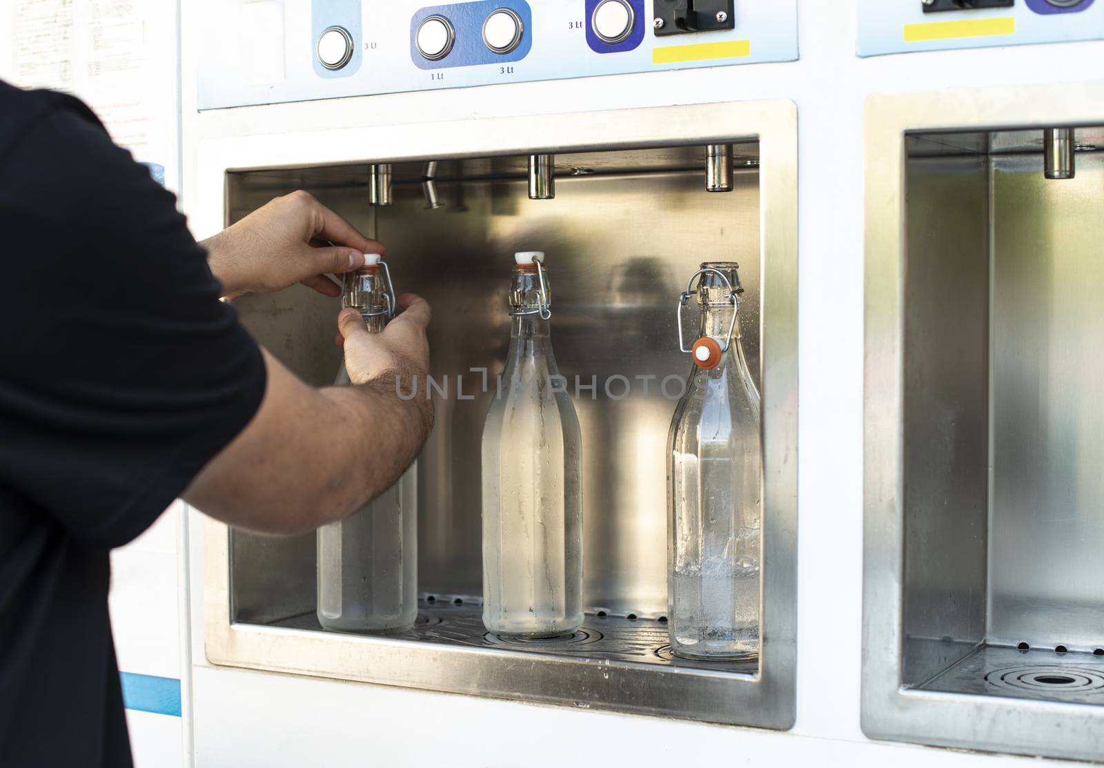 Mineral Water machine on the street. Filling mineral water bottles from a water dispenser. Pay and load drinking water.