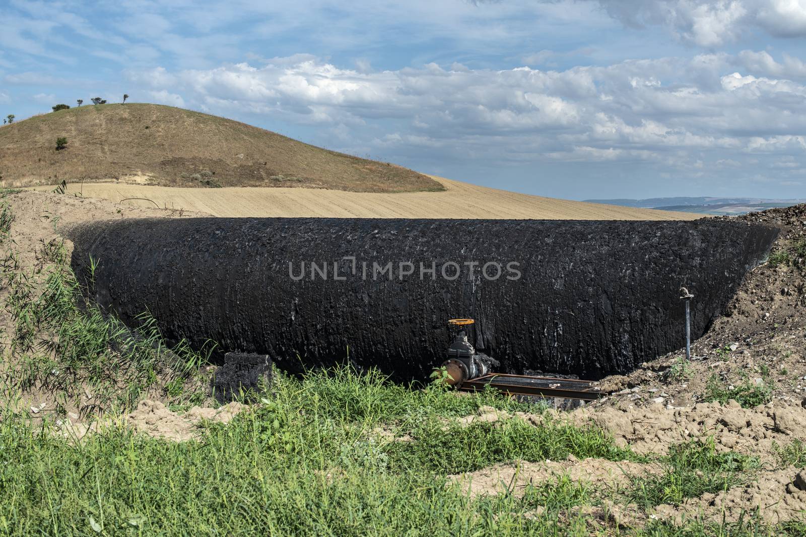 Black Oil pipeline goes out above the ground. Oil-stained pipe.  by deyan_georgiev