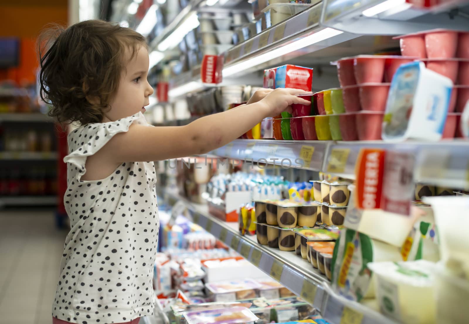 Little girl buying yogurt in supermarket. Child in supermarket s by deyan_georgiev