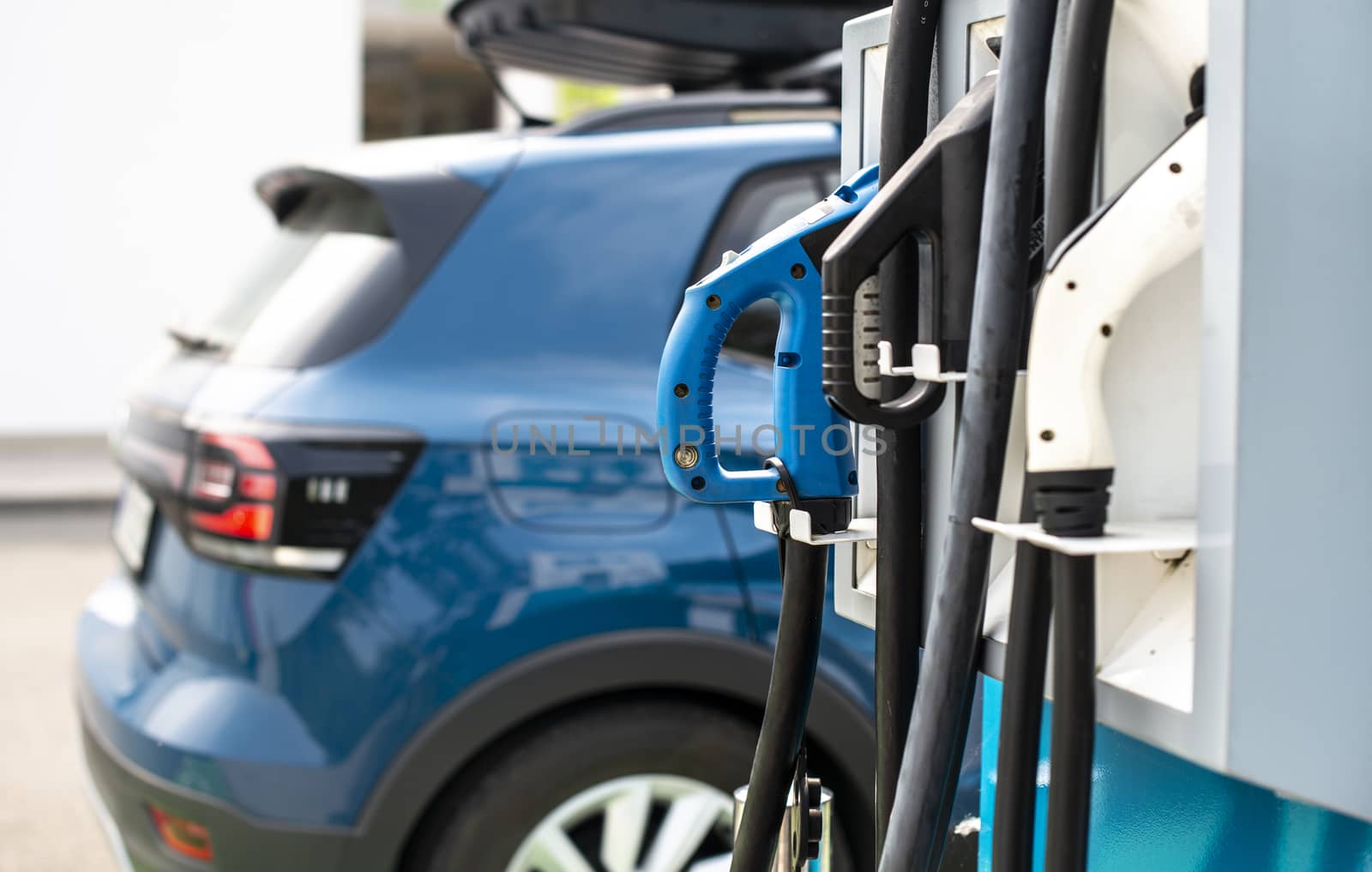 Electric car on gas station. Blue car and electric plug for charging. Ecology green fuels concept.