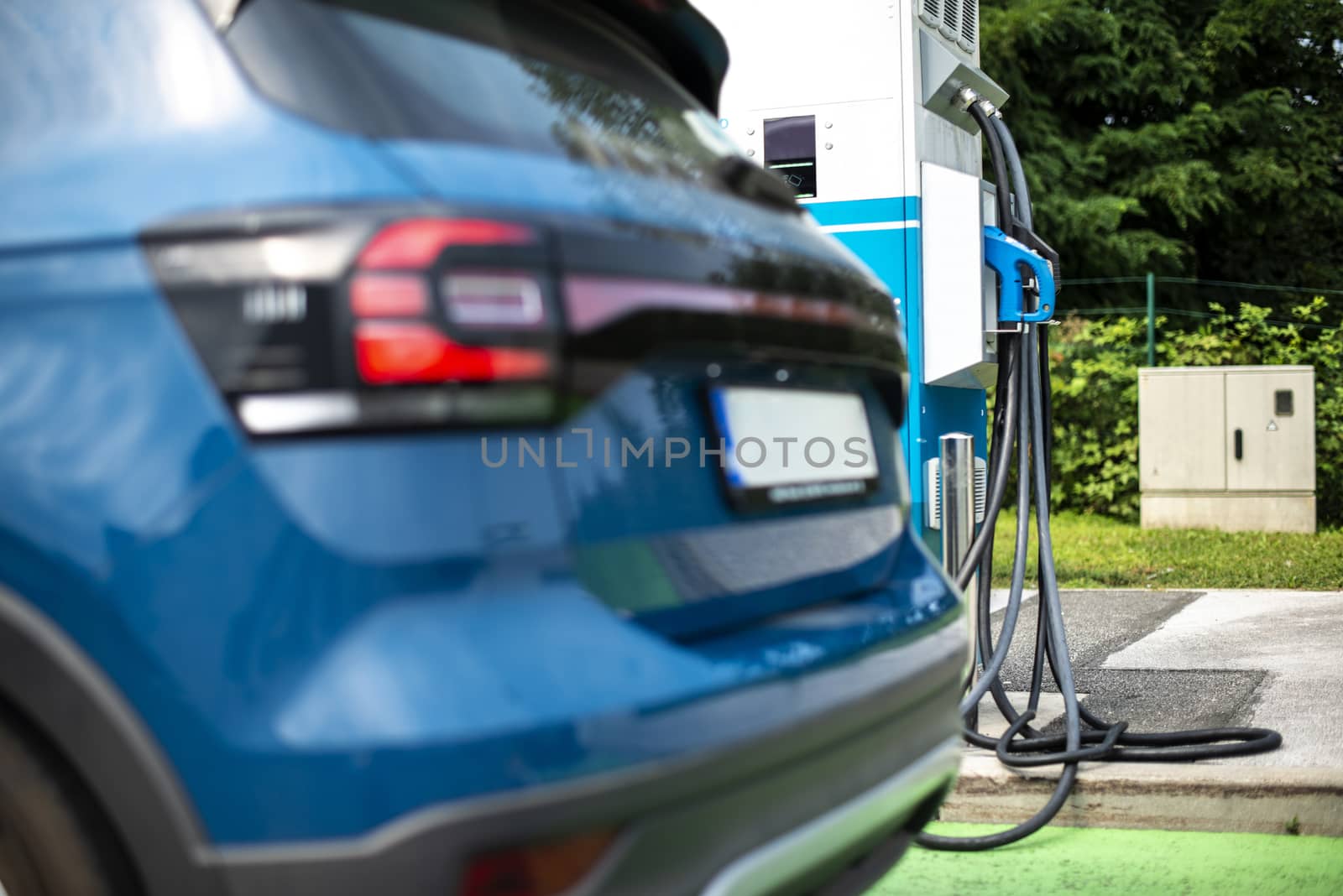 Electric car on gas station. Blue car and electric plug for charging. Ecology green fuels concept.