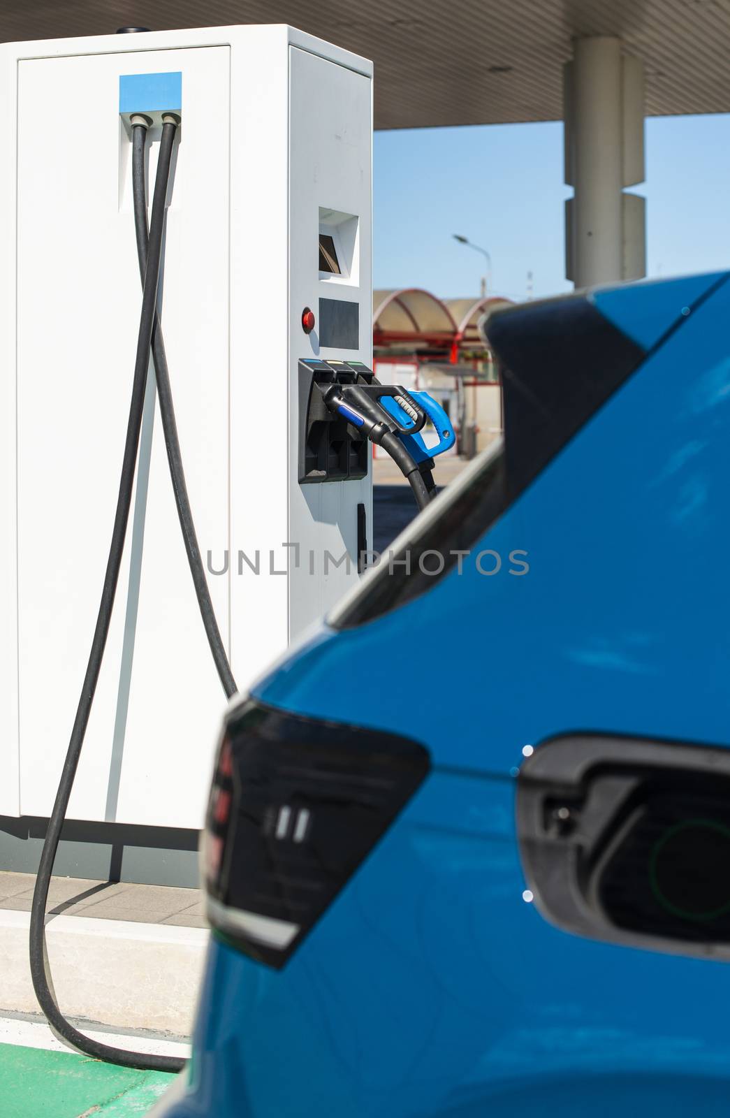 Electric car on gas station. Blue car and electric plug for charging. Ecology green fuels concept.