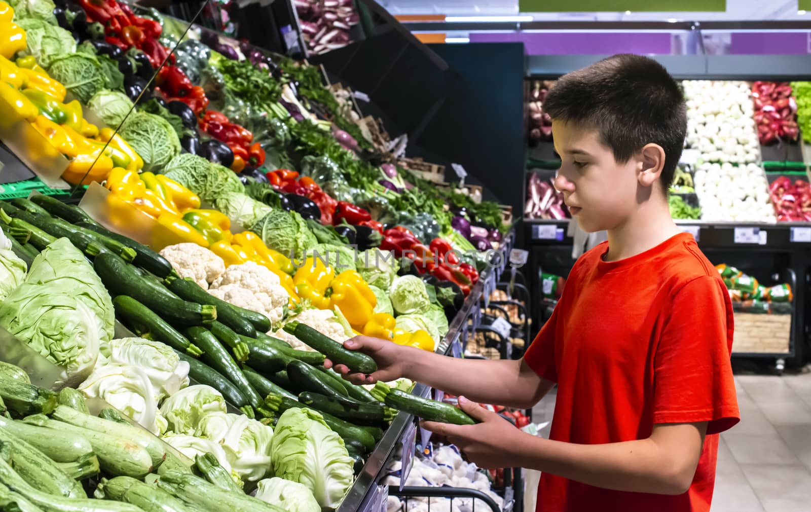 Child selecting vegetables on shelf in supermarket. by deyan_georgiev