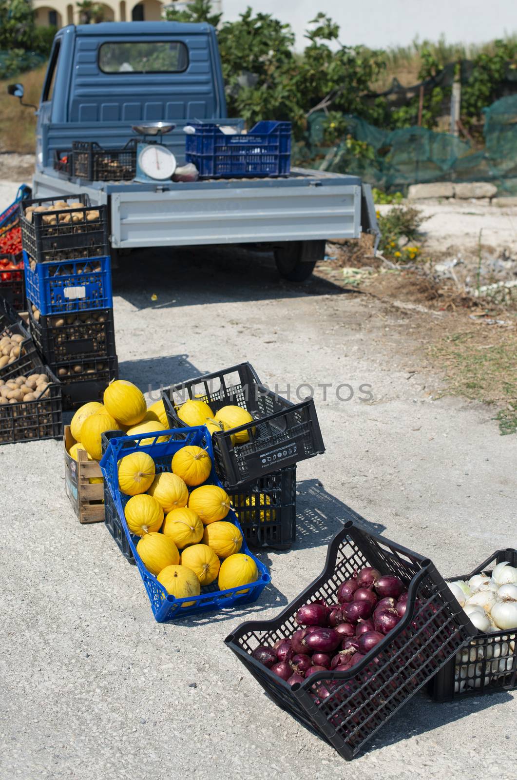 Small italian apo truck. Street vegetable market. Farmer sale melons and onion on the street in Italy.