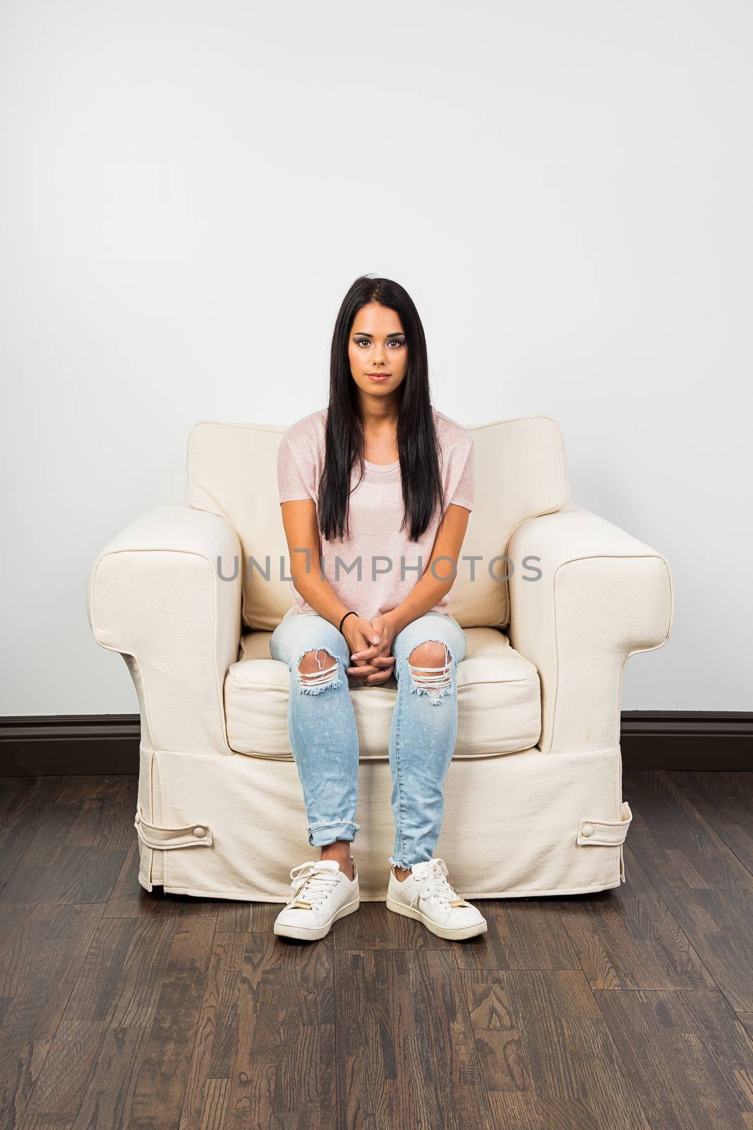 Mid-twenties young woman with long black hair sitting on a couch