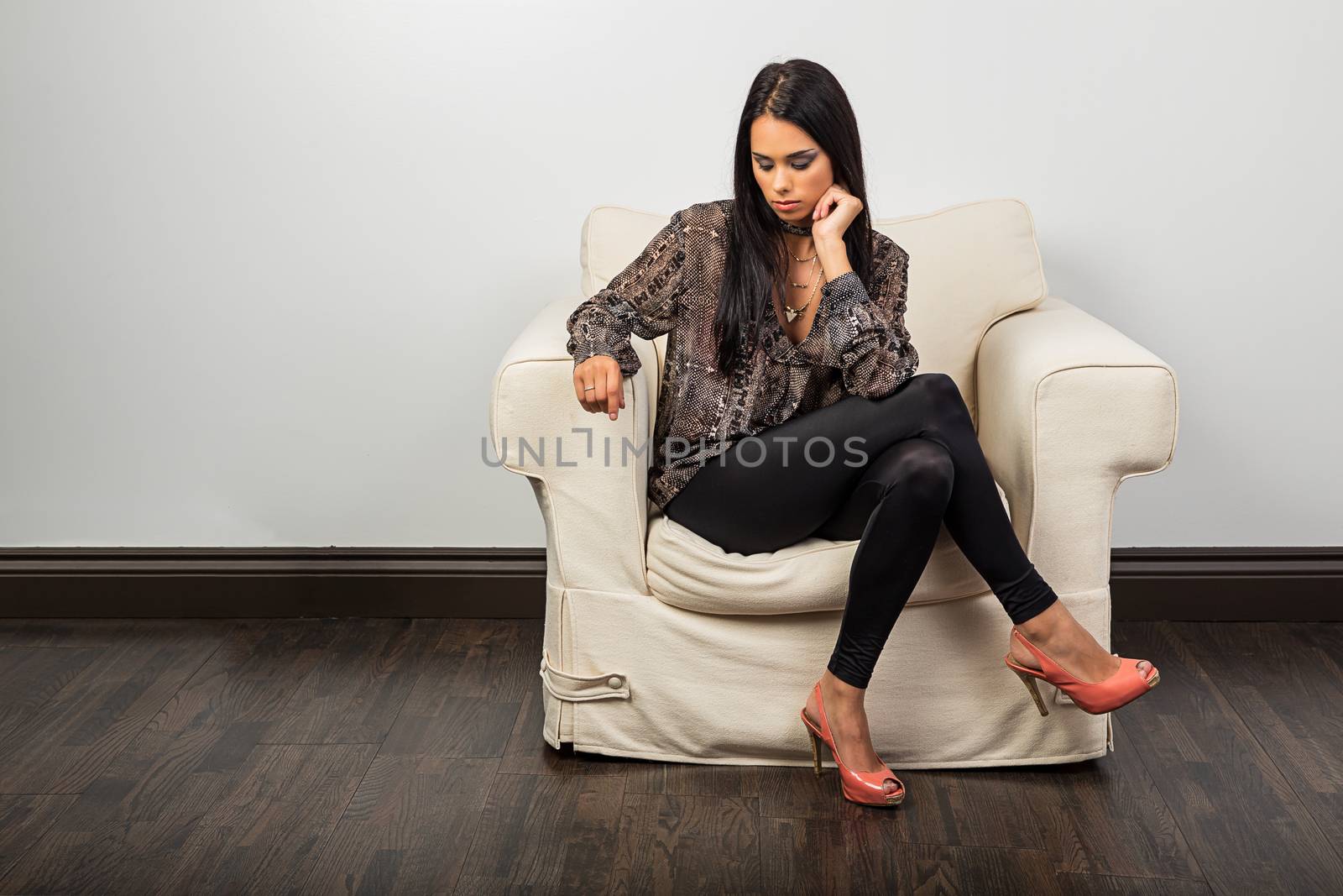 Young woman, sitting on a couch, looking down at the floor