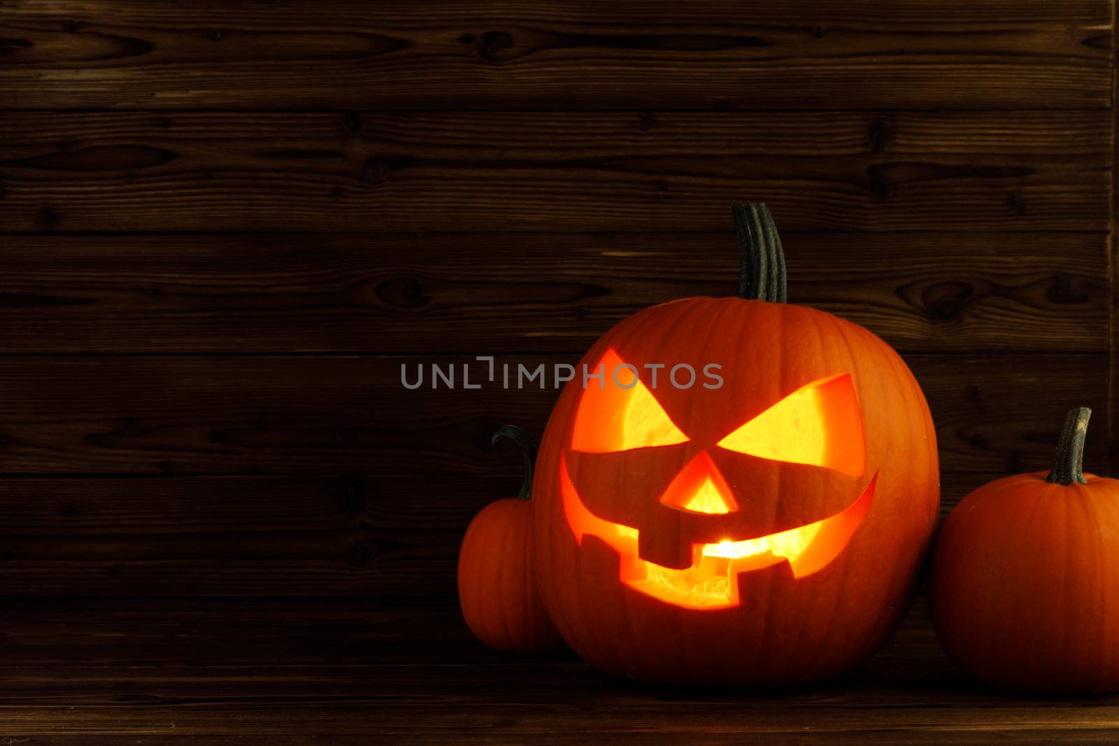 Glowing Halloween pumpkin heads jack o lantern on wooden background