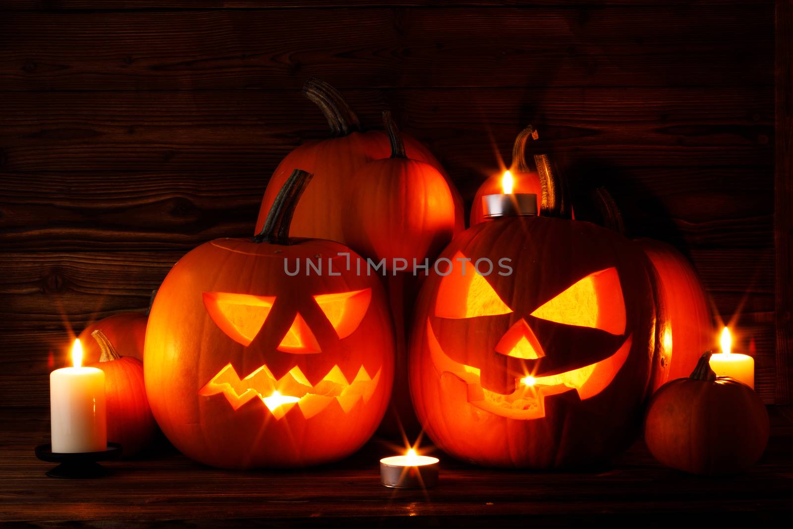 Group of Halloween pumpkin head jack o lantern and candles on dark wooden background