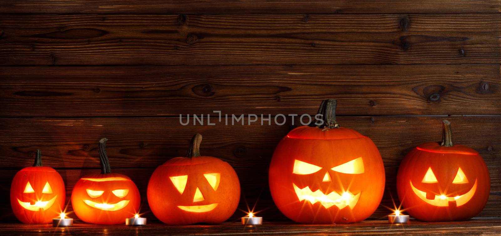 Group of Halloween pumpkin head jack o lantern and candles on dark wooden background