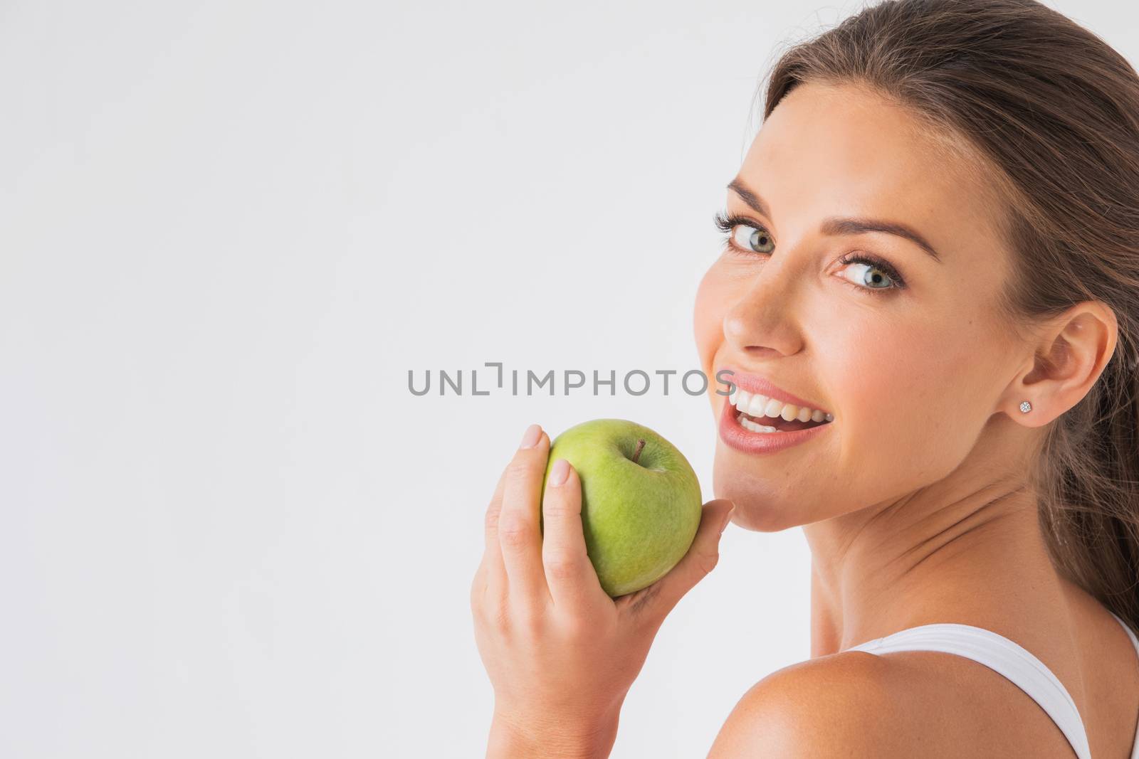 Beautiful woman with healthy white teeth holding green apple on white background