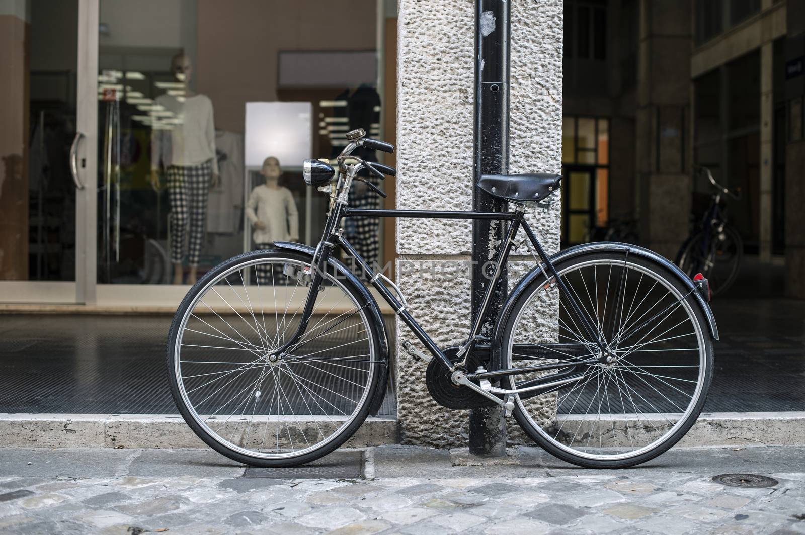 Black bike in front of fashion shop on italian street. Typical italian style.