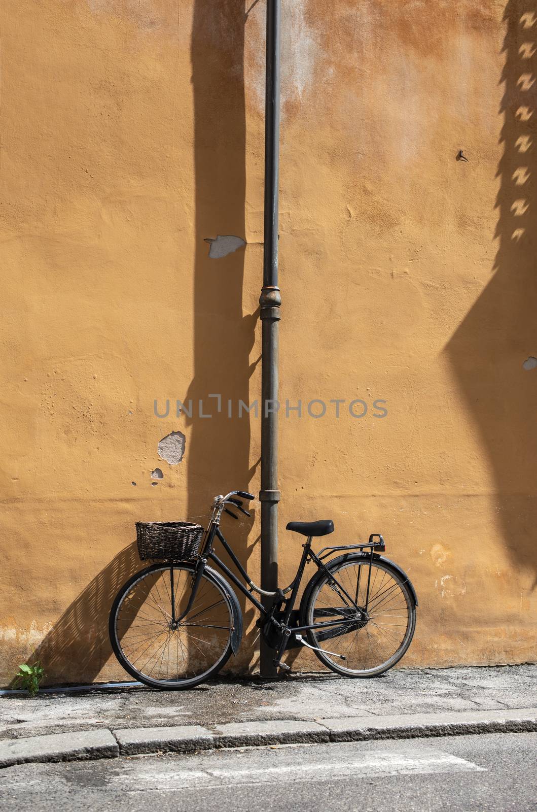 Black bike with basket on italian street. Typical italian architecture on background. Sunny day. Typical italian style.
