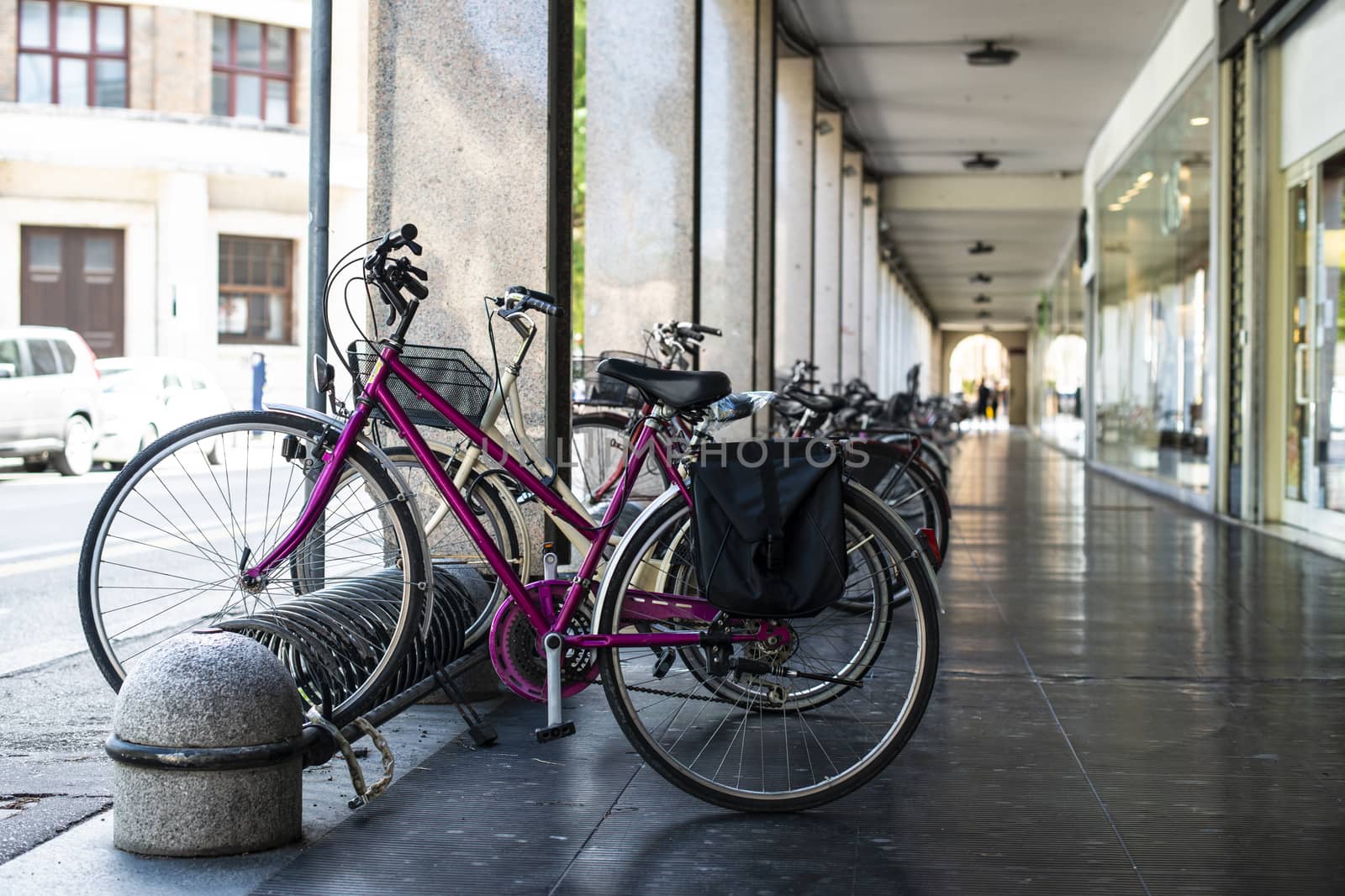 Bikes mounted on a bicycle stand on italian street.  by deyan_georgiev