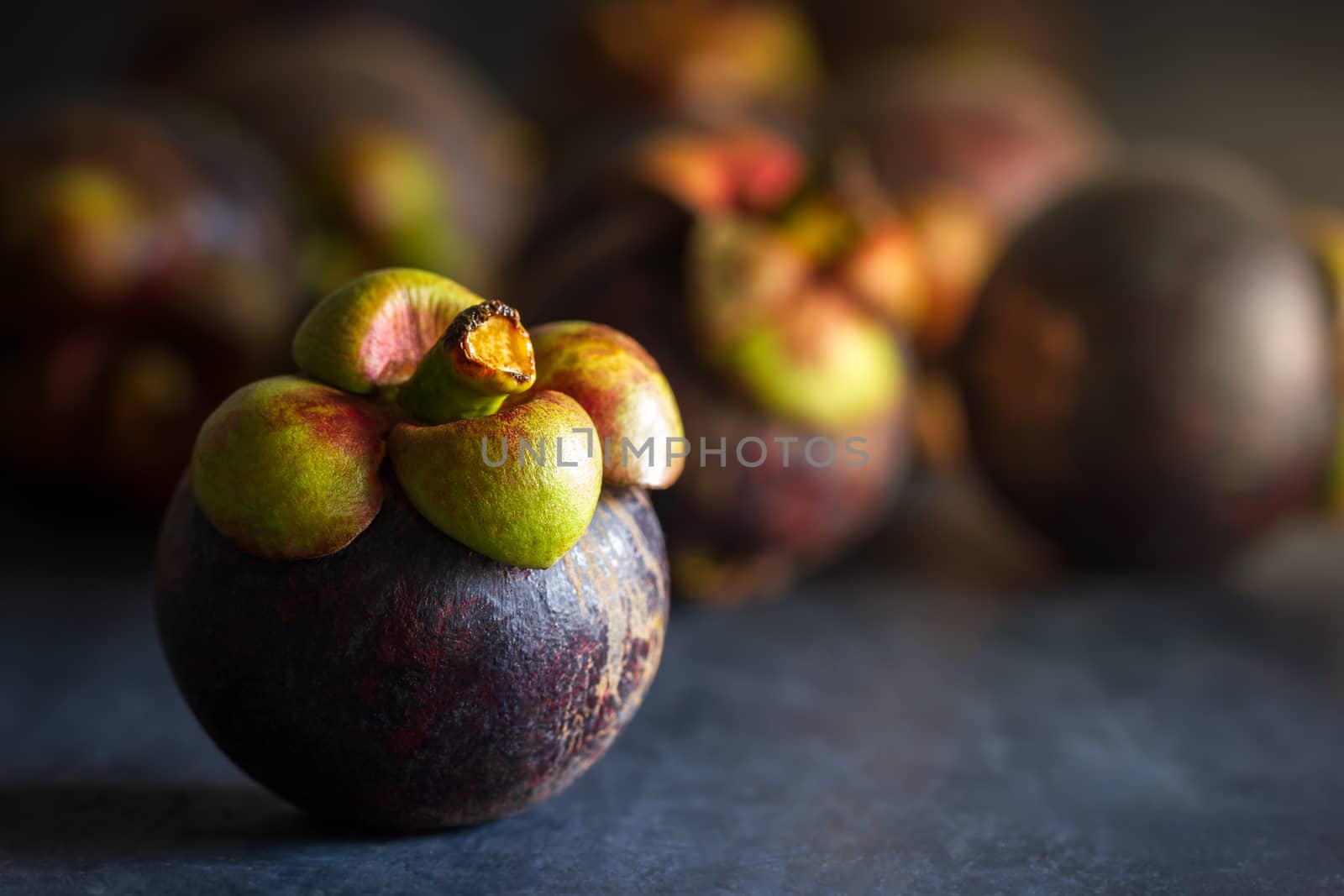 Mangosteen fruit on black cement floor and morning light. Is a seasonal fruit in Thailand. Closeup and copy space for text.