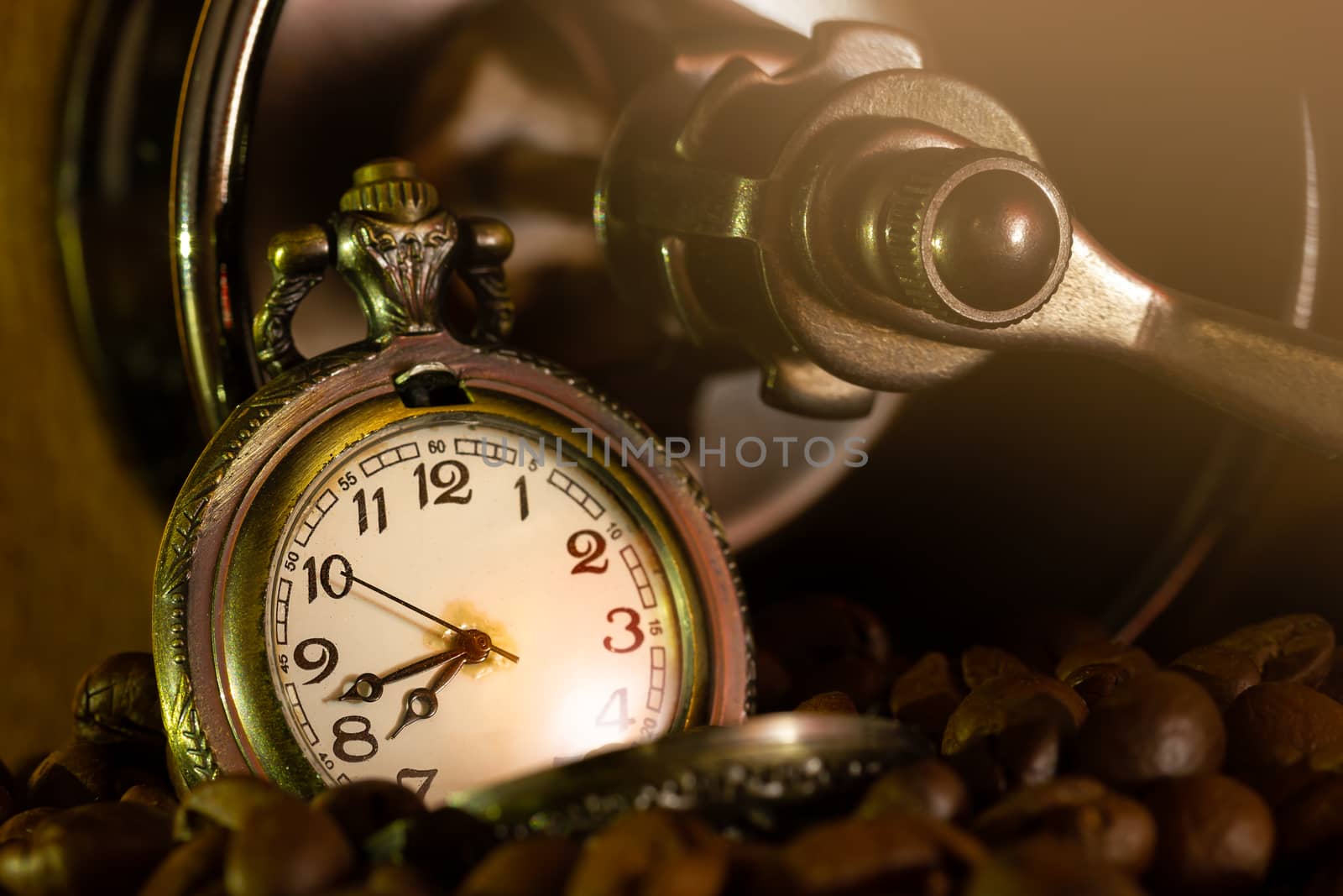 Coffee bean and pocket watch in manual grinder on table. Closeup and copy space. Concept of coffee time in morning.