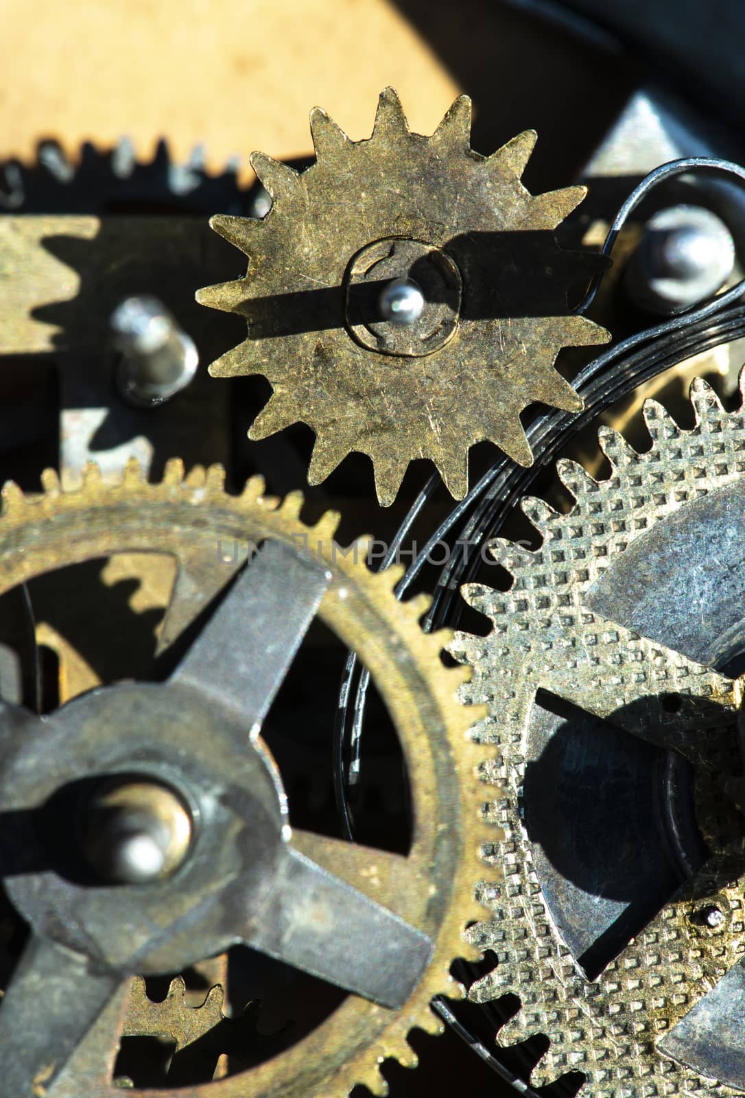 Close up metal gears mechanism. Golden colours. Hard light. Clock interior mechanism parts.