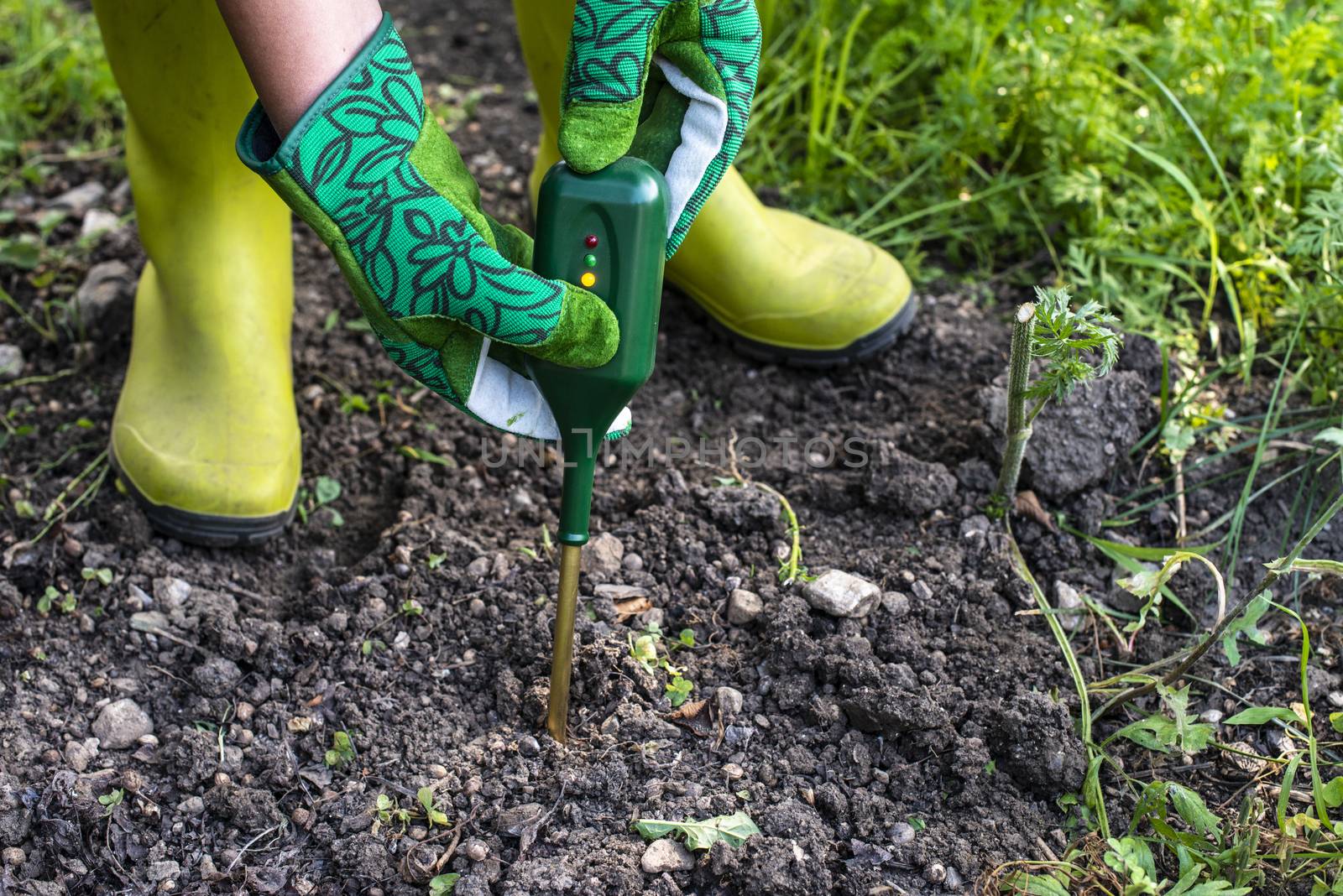 Nutrients soil meter. Measure soil for nitrogen content with digital device. Woman farmer in a garden. Concept for new technology in the agriculture.