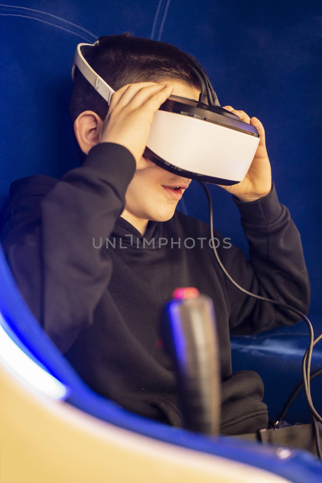 Child watching movie with VR glasses. Blue illuminated cabin with joysticks. Special effects. Technology and entertainment concept with virtual reality glasses.