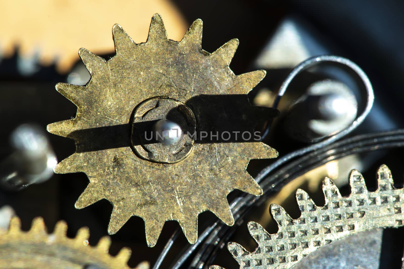 Close up metal gears mechanism. Golden colours. Hard light. Clock interior mechanism parts.