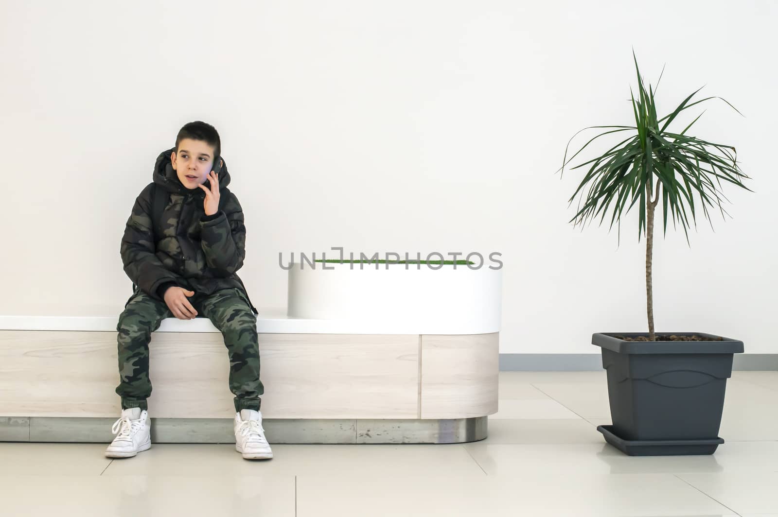 Teenager talking on smartphone in modern commercial center. Tech by deyan_georgiev