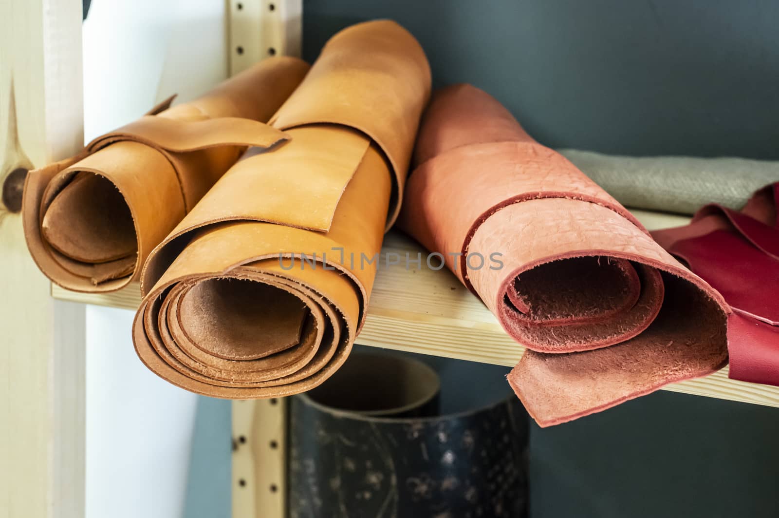 Many rolls leather on shelf in leather workshop.