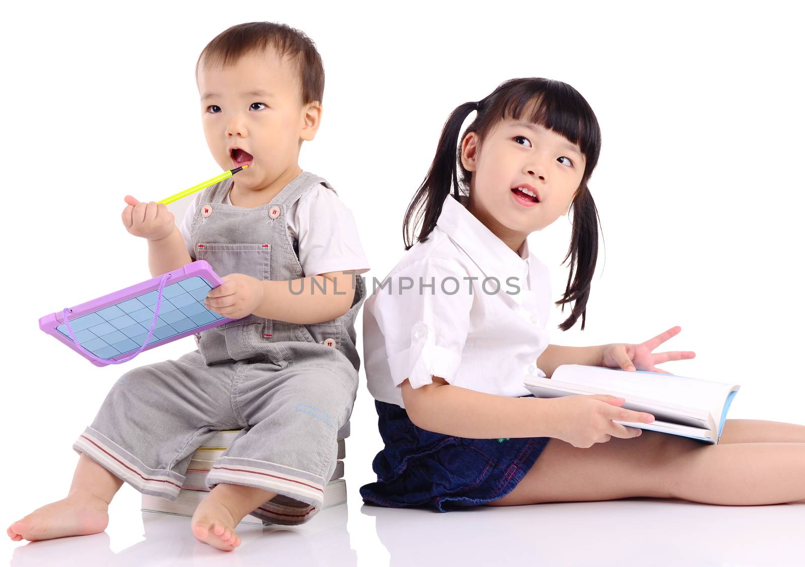 Asian kids sitting on the floor,reading book and playing with toy