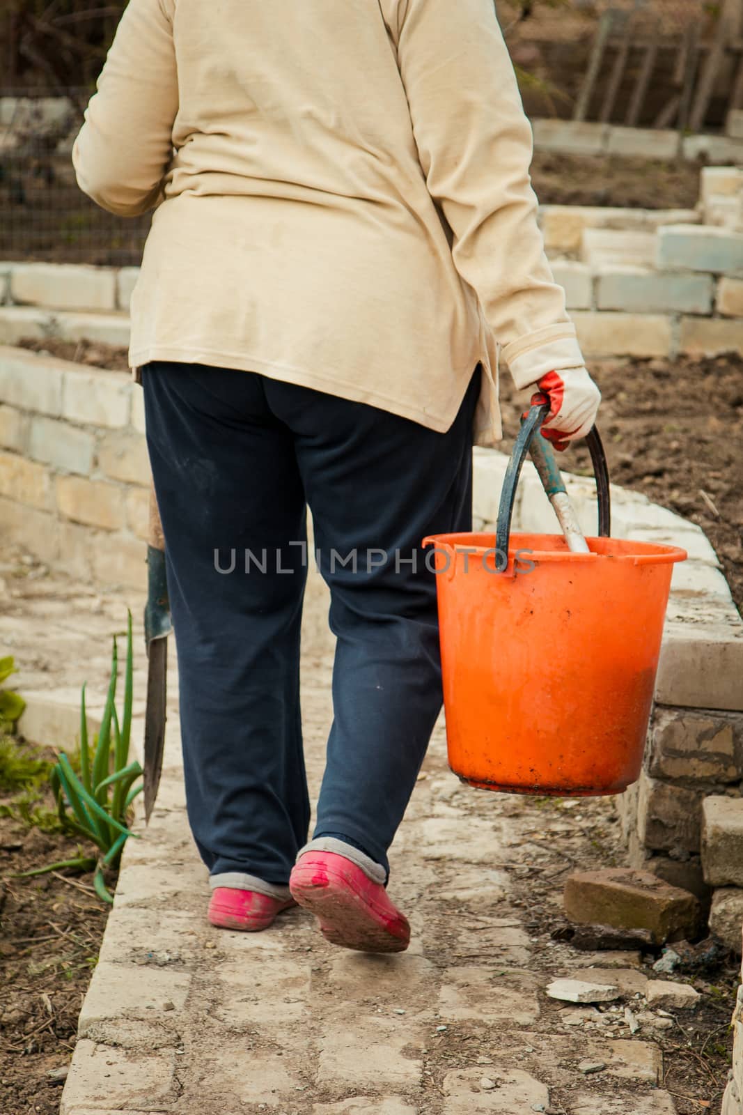 Farmer woman carrying an orange bucket walking outdoor