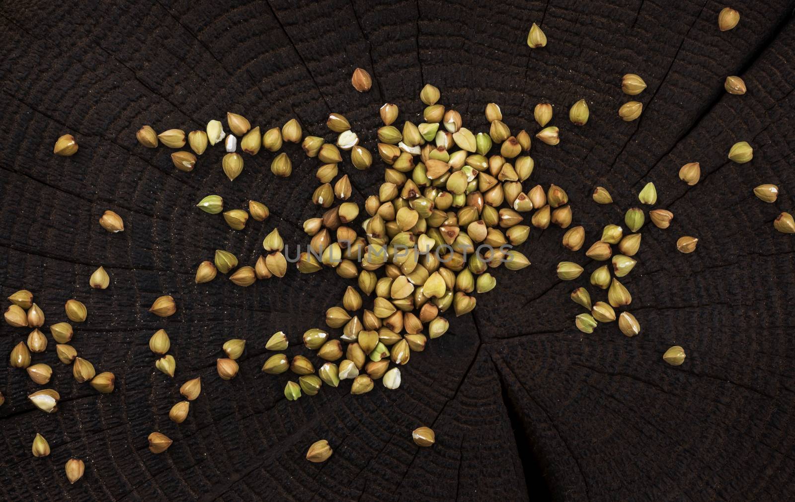 Heap of green buckwheat grain on black wooden background, top view