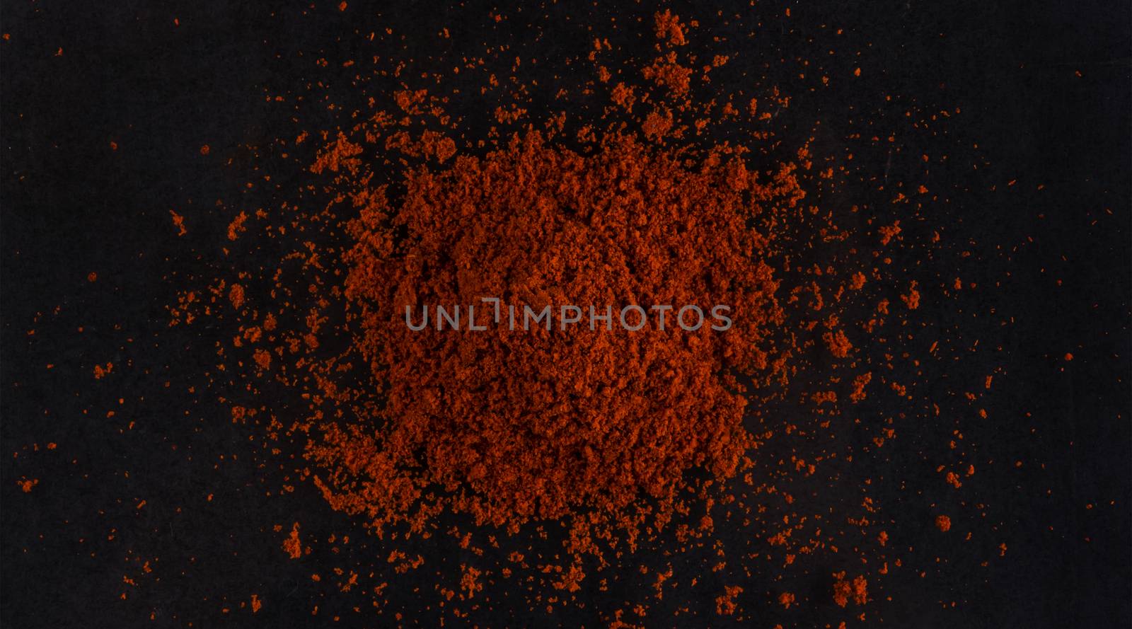 Pile of red paprika powder isolated on black background, top view