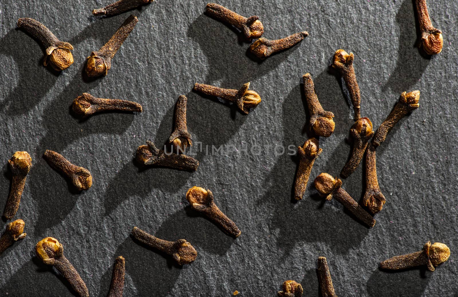 Dried Cloves on dark stone background. Natural hard light. Spice by deyan_georgiev