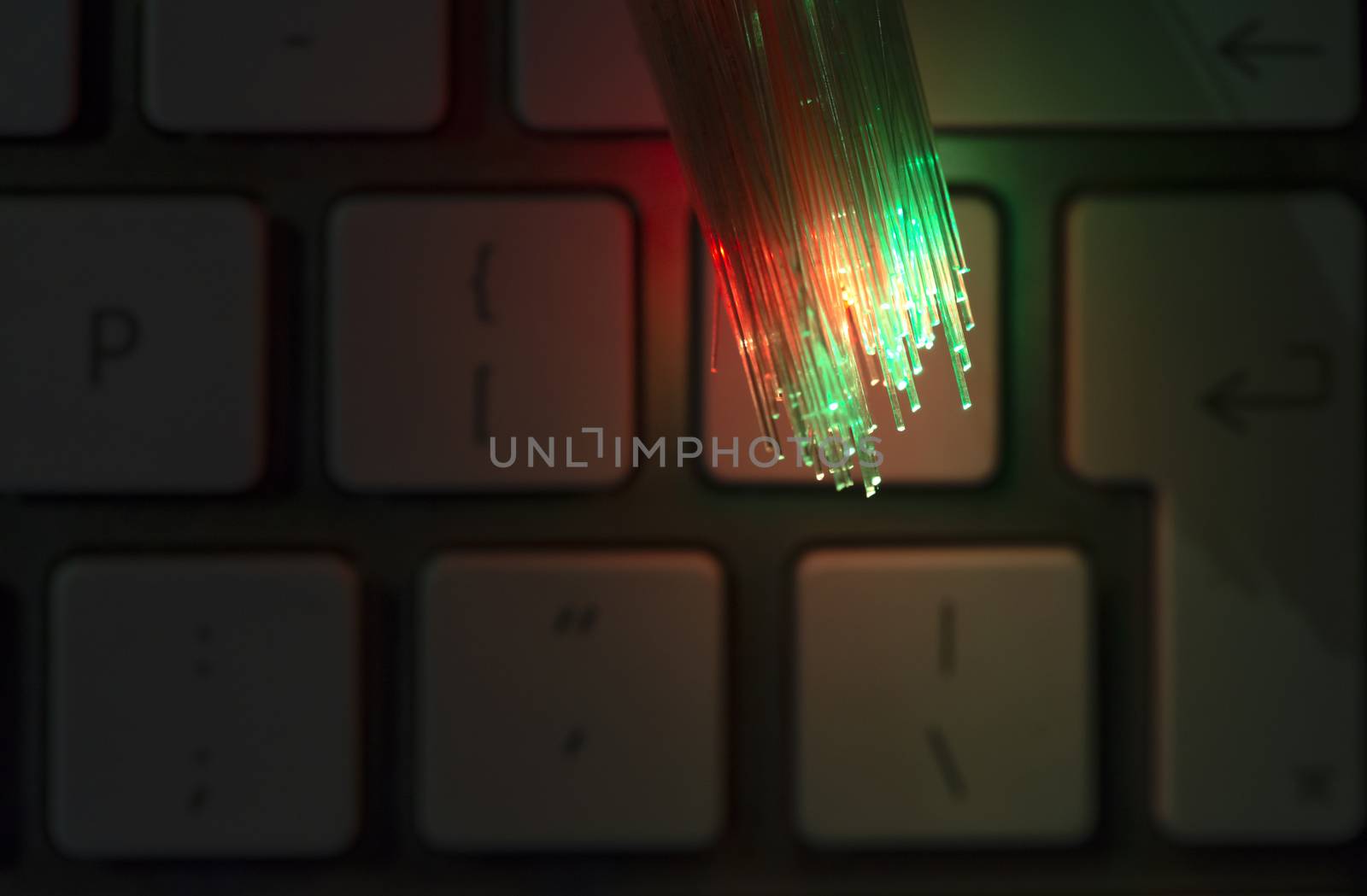 Colourful optic fibers illuminated on keyboard. High speed internet concept. Data transfer optic fiber cable. Bunch of many optical fibers, glowing different colors. Technology background.