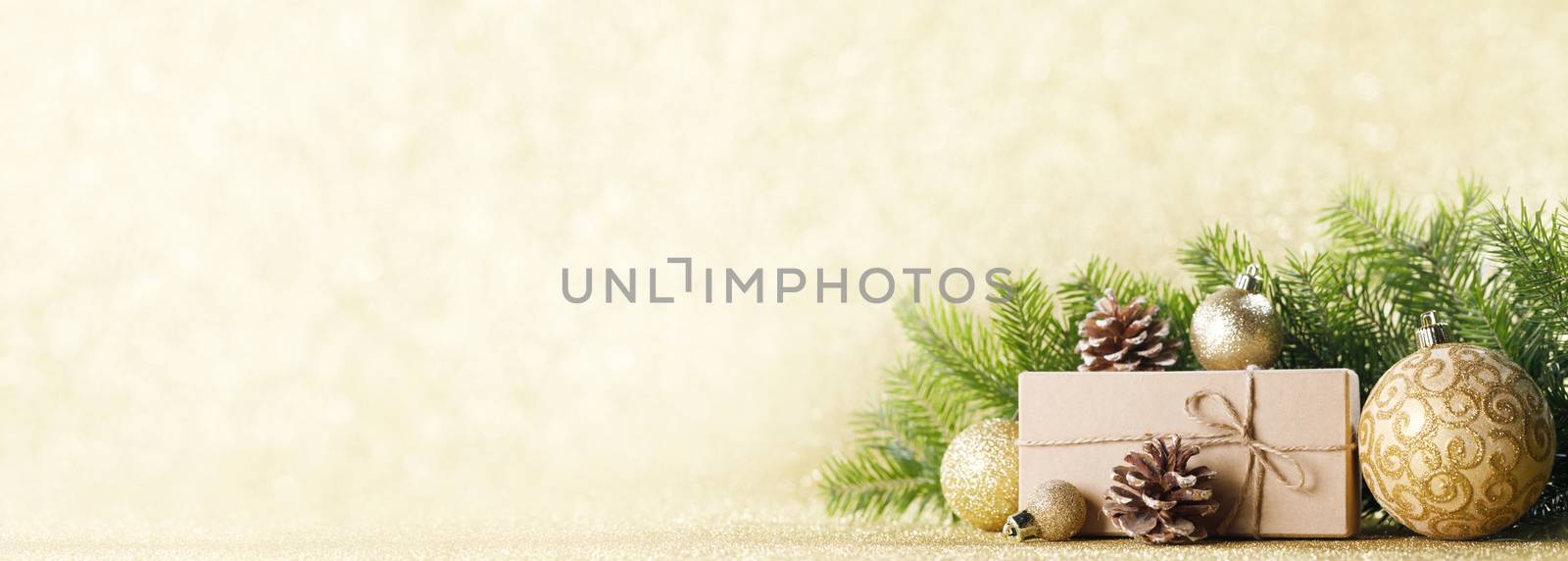 Christmas or new year decorations, craft paper gift box, pine tree branches and cones and balls with bokeh lights background, copy space