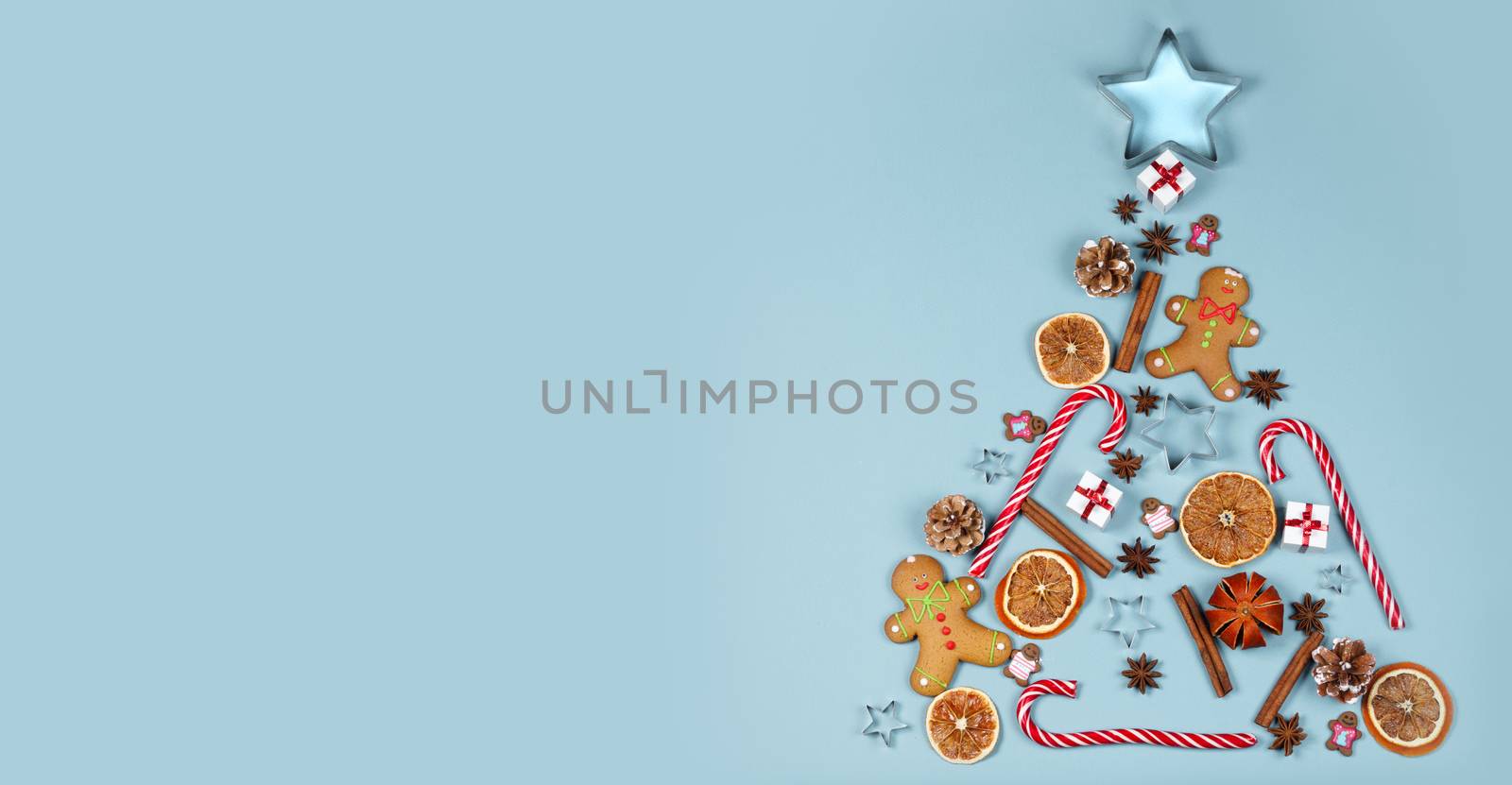 Christmas tree symbol composition. Ginger cookies caramel candy canes mold star form gifts orange and baubles, flat lay with copy space