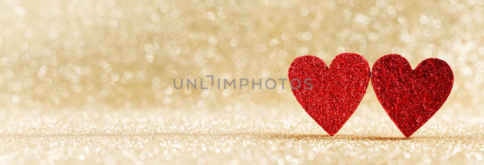 Two small handmade red glitter hearts on bright golden lights bokeh background Valentines day card