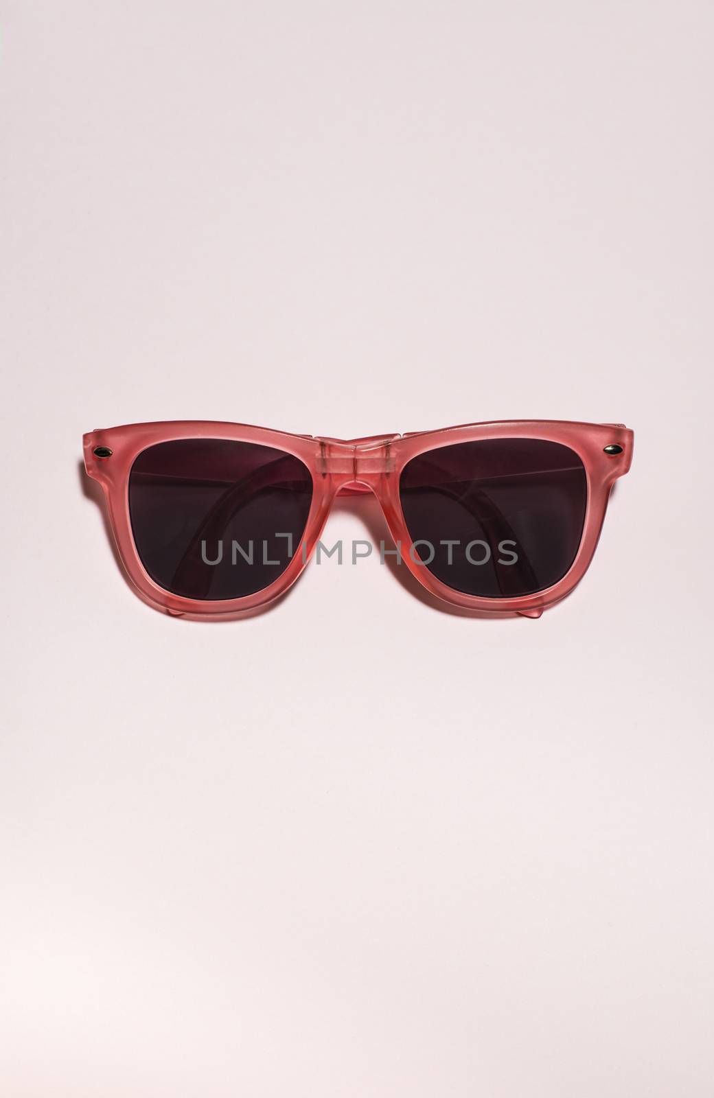 Red bright sunglasses on a pastel pink background. Summer time, party and vacations concept. Minimalism with sunglasses.