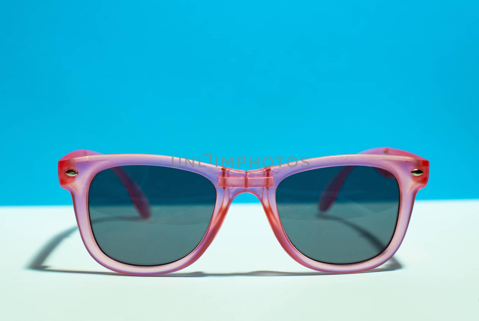 Pink bright sunglasses on a pastel blue background. Summer time, by deyan_georgiev