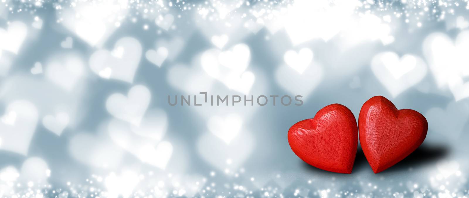 Two small handmade red wooden hearts on bright blue lights bokeh background Valentines day card