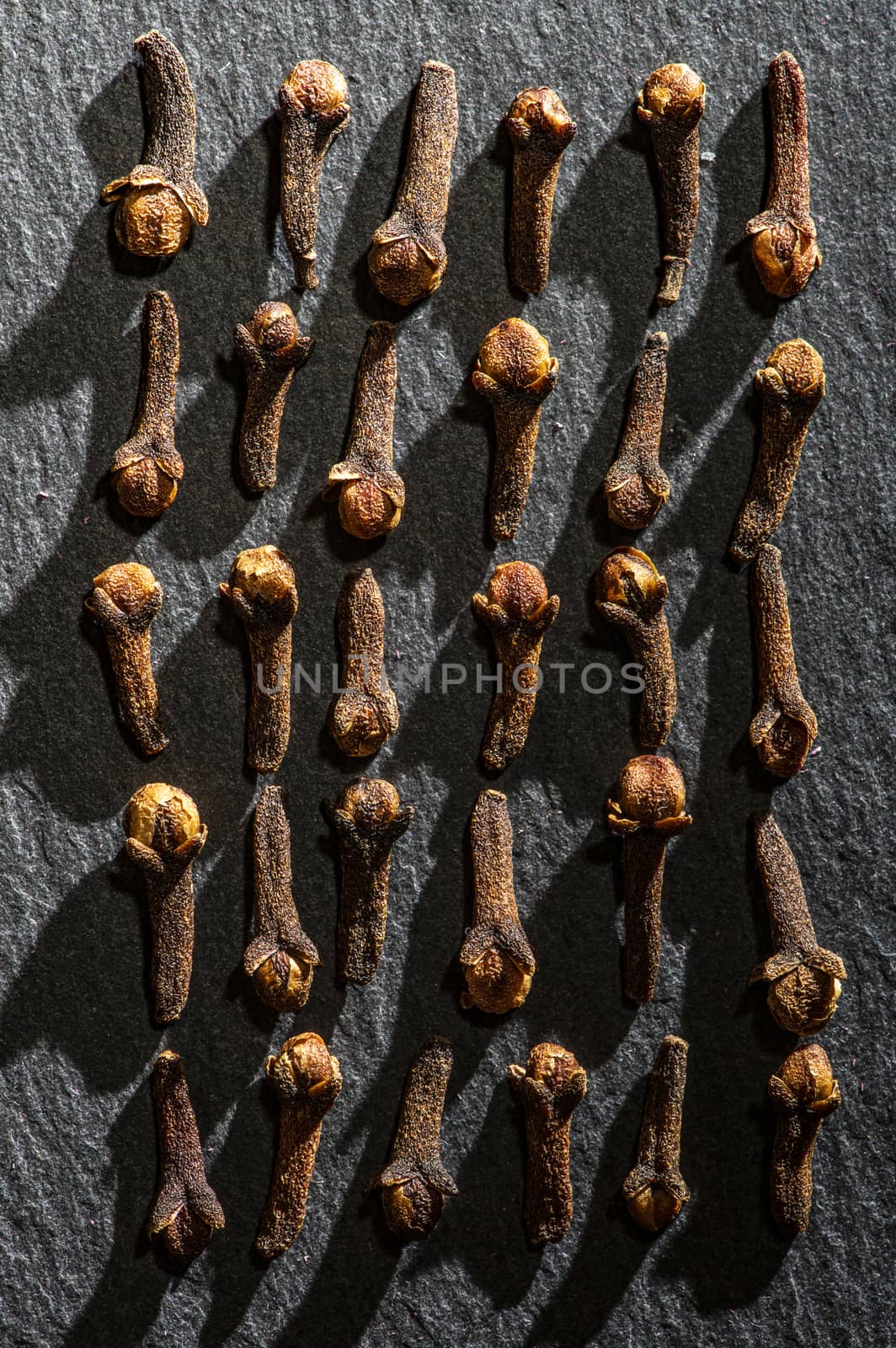 Dried Cloves on dark stone background. Natural hard light. Spice cloves close-up shot. Cooking with aromatic condiments conceptual background.