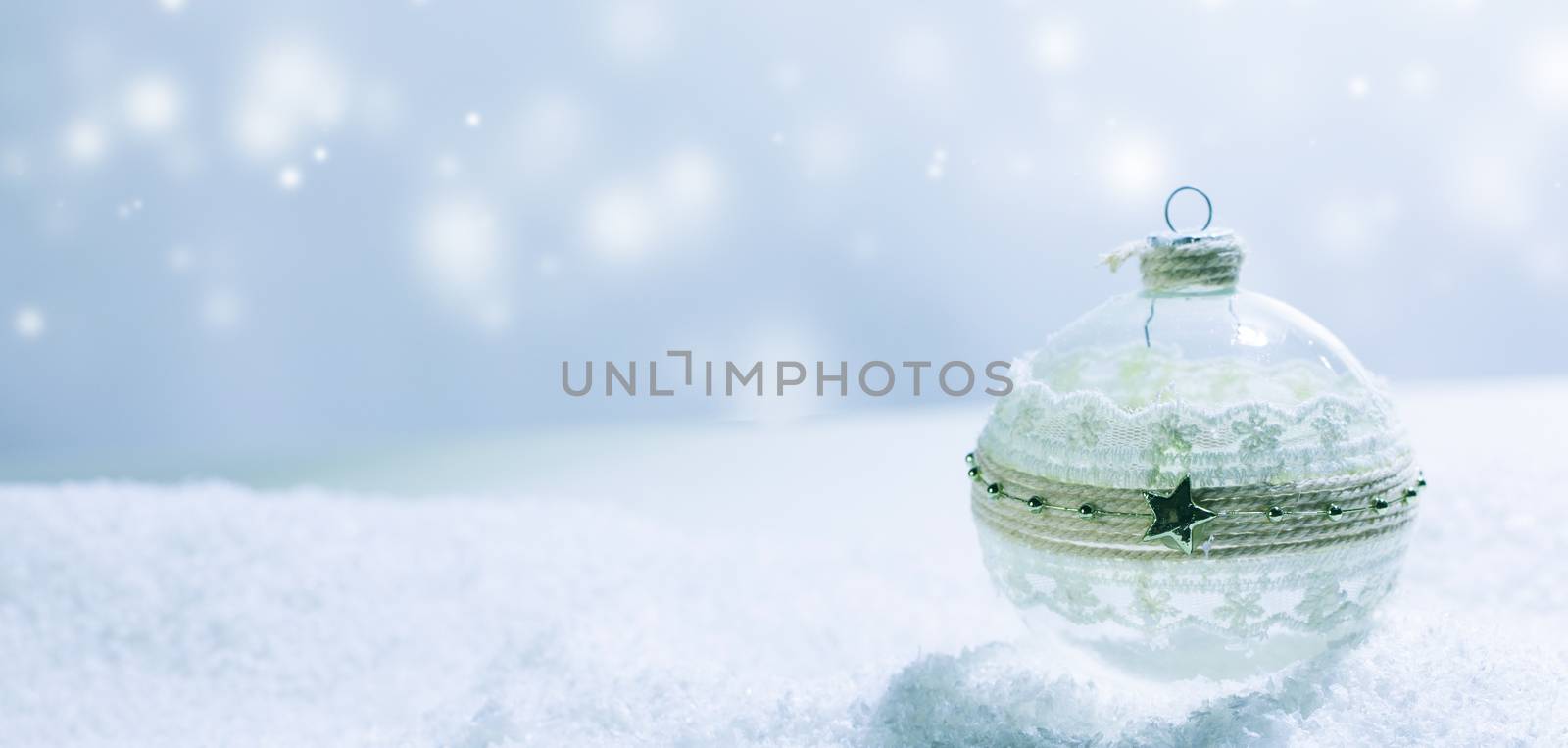 Christmas decorated glass ball in snow on blue bright background