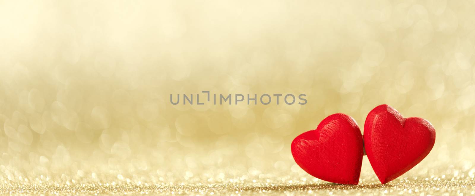 Two small handmade red wooden hearts on bright golden lights bokeh background Valentines day card