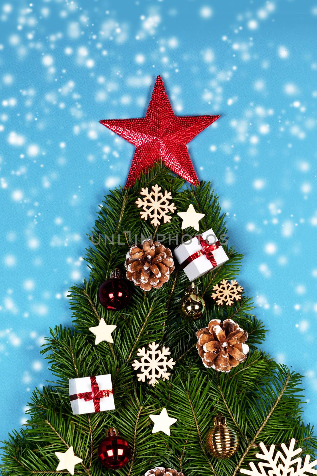 Christmas tree made of natural spruce branches deecor with red star on blue background, flat lay card with copy space