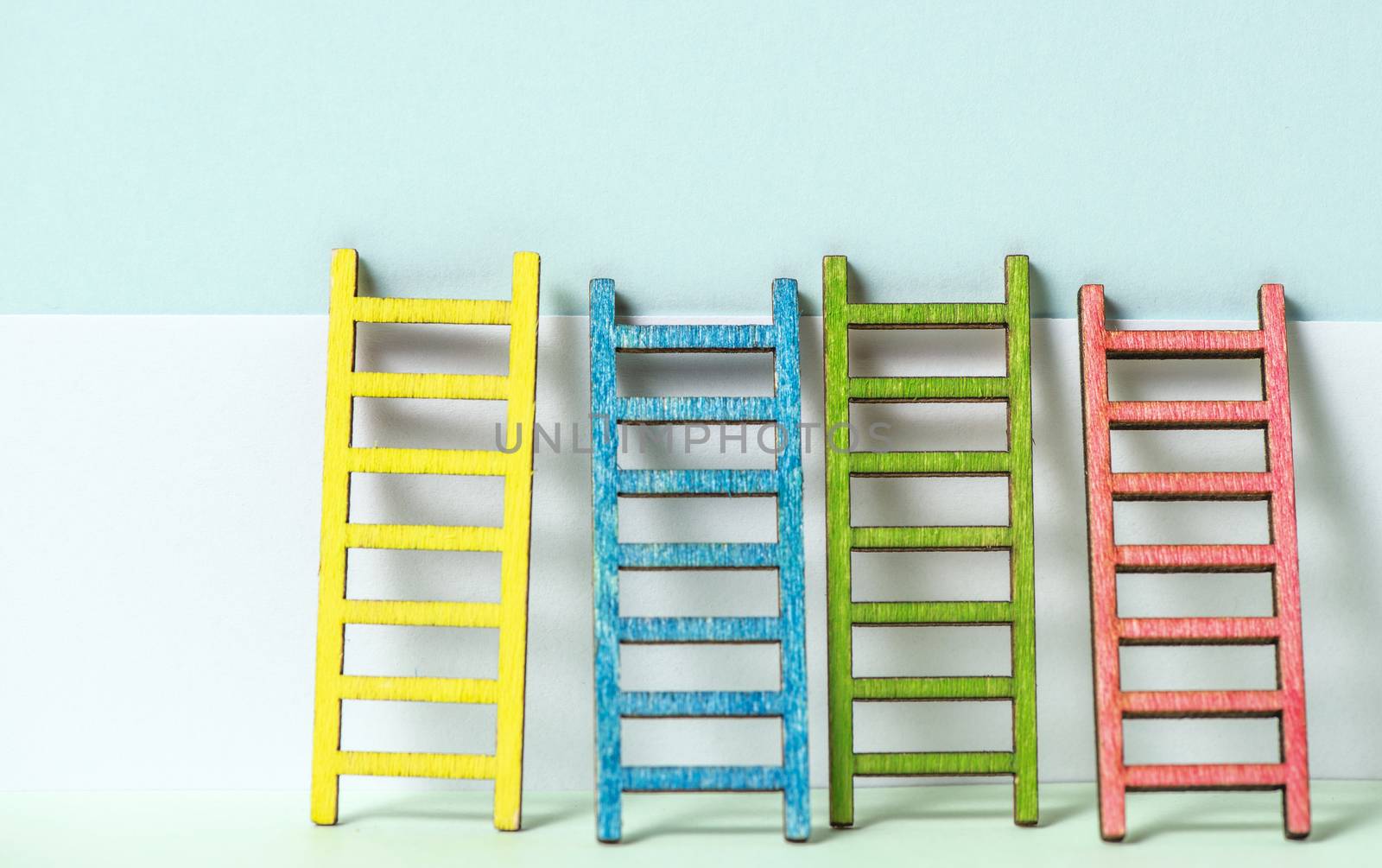 Multicoloured ladders on wall. Pastel tones. Concept for success and growth. Business metaphors.