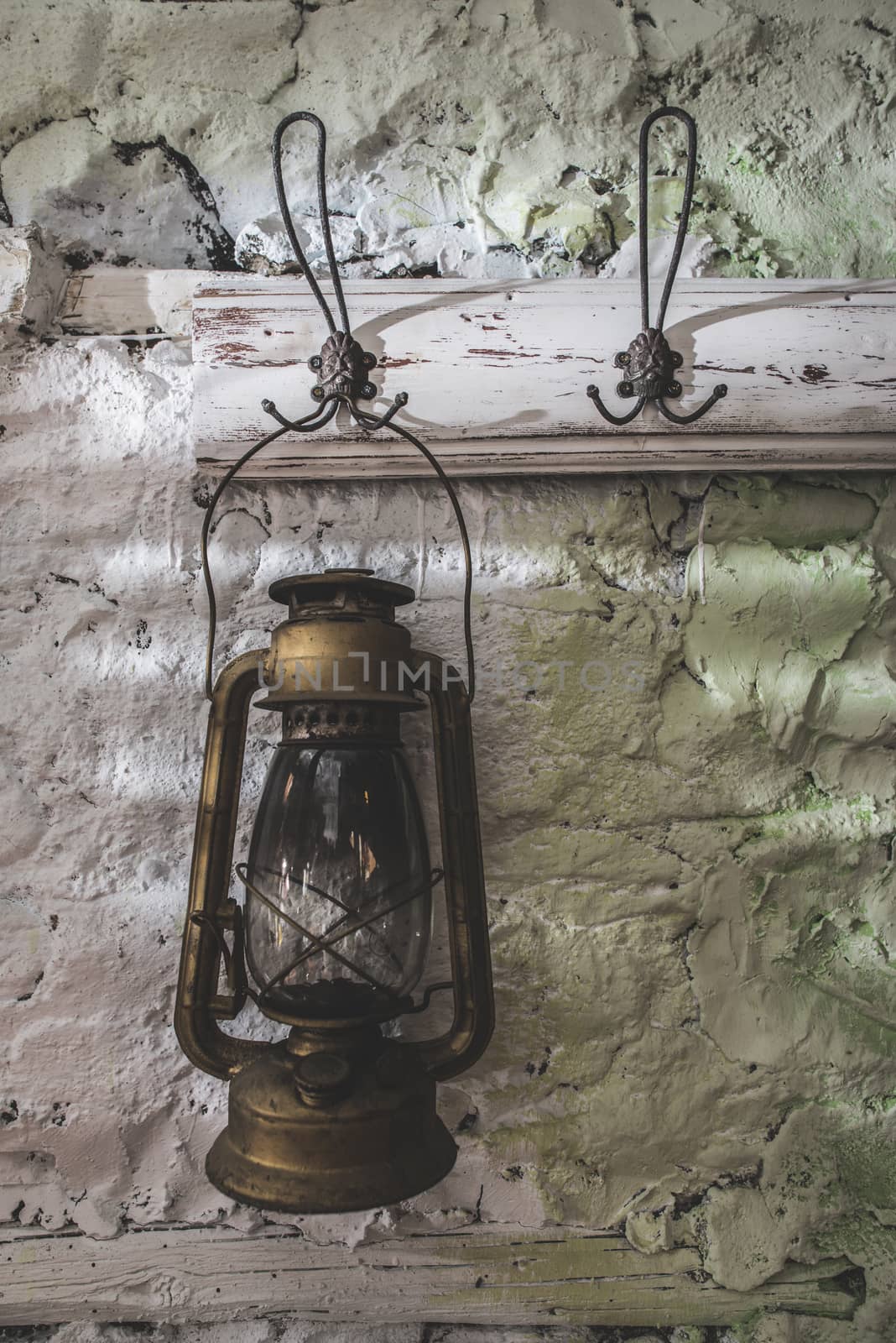 Old vintage lantern lamp on painted stone wall. Hooked lantern on hanger. 