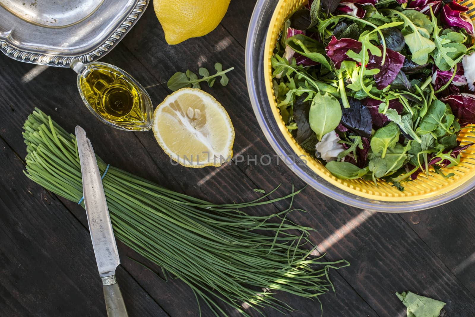 Spring green salad of baby spinach, herbs, arugula and lettuce. Dressing of yogurt, olive oil, honey and lemon.Vegetables for preparing salad on dark table.Concept for healthy food and diet.