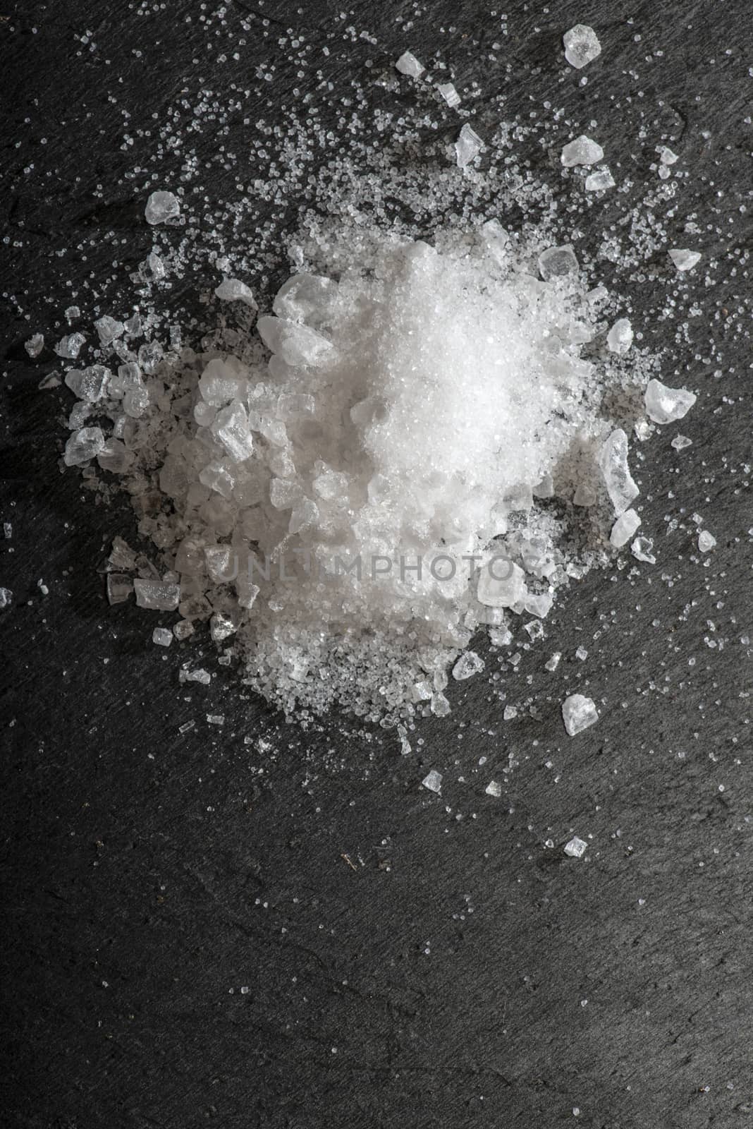 White salt crushed on dark stone background. Close-up Big pieces of salt. Heap pouder salt and natural light.