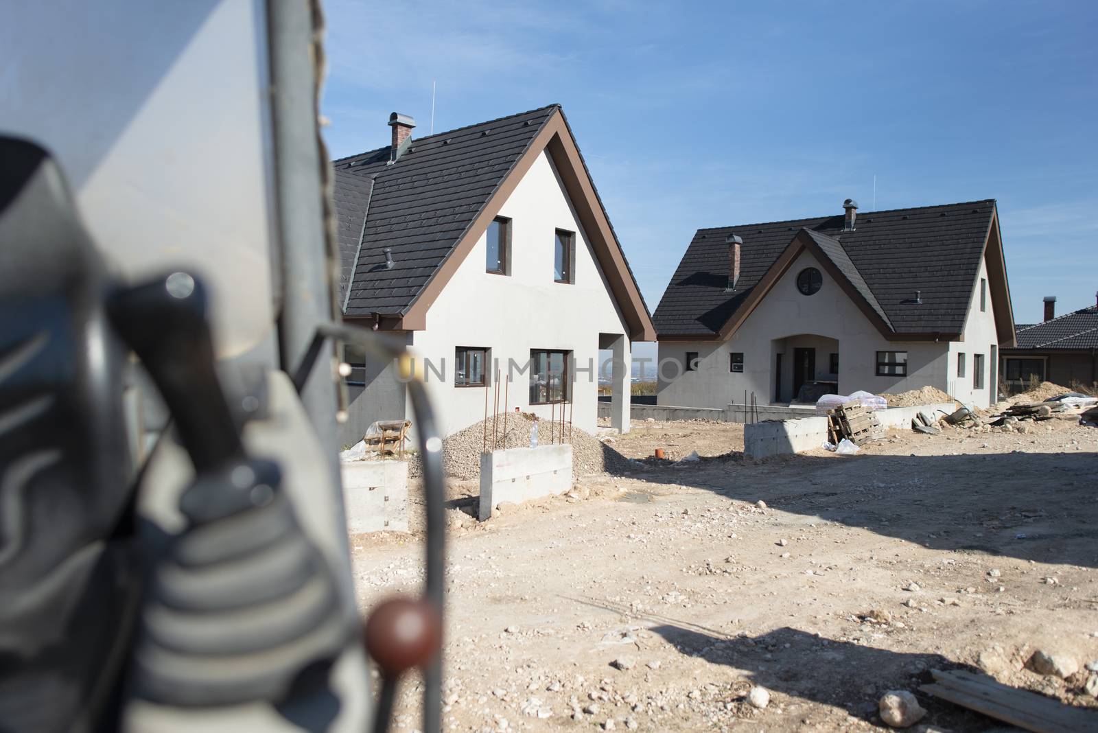 Excavator and newly built houses on construction site