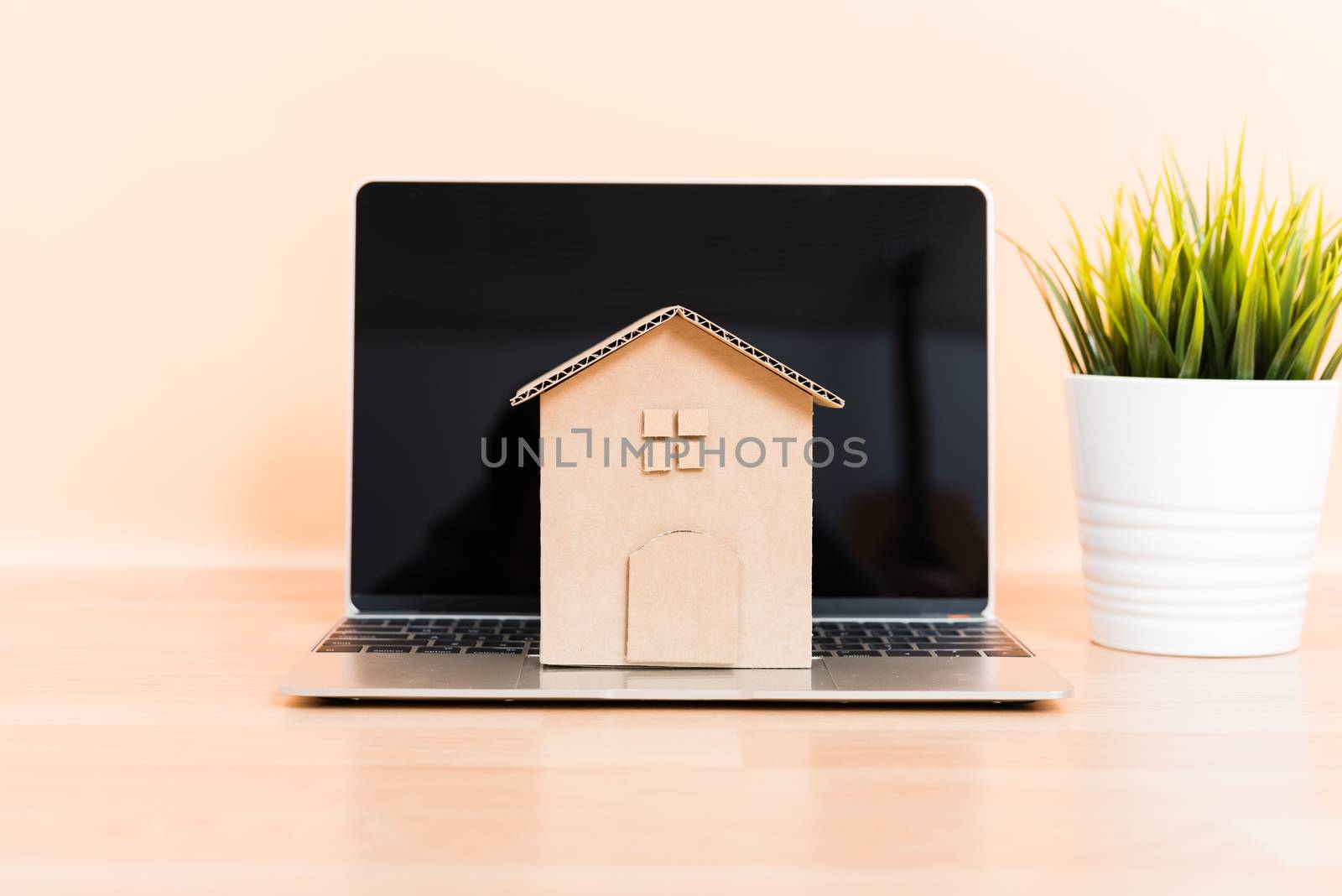 Cardboard paper model house and computer laptop, property mortgage rent buy concept