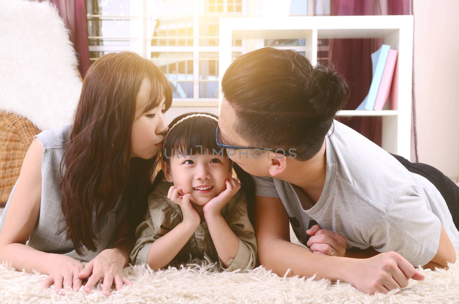 Asian parent kissing their daughter at home