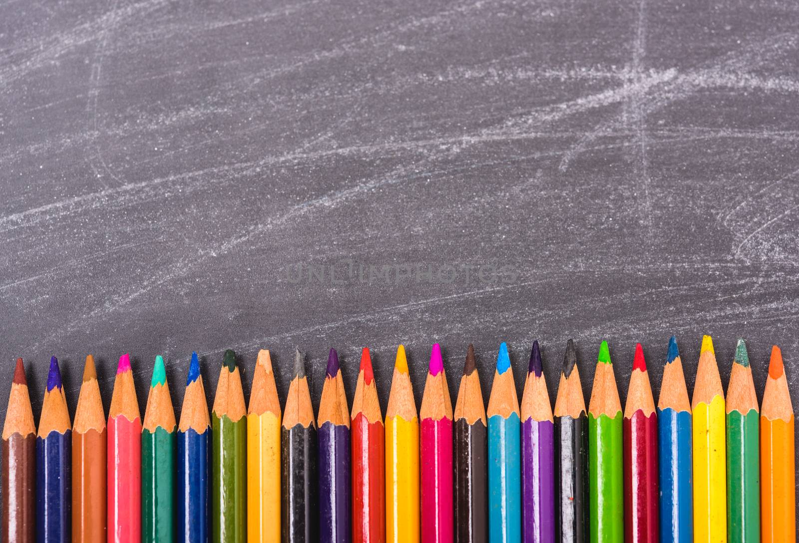 Multi Color pencils on crowd on blackboard and have chalkboard by Sorapop