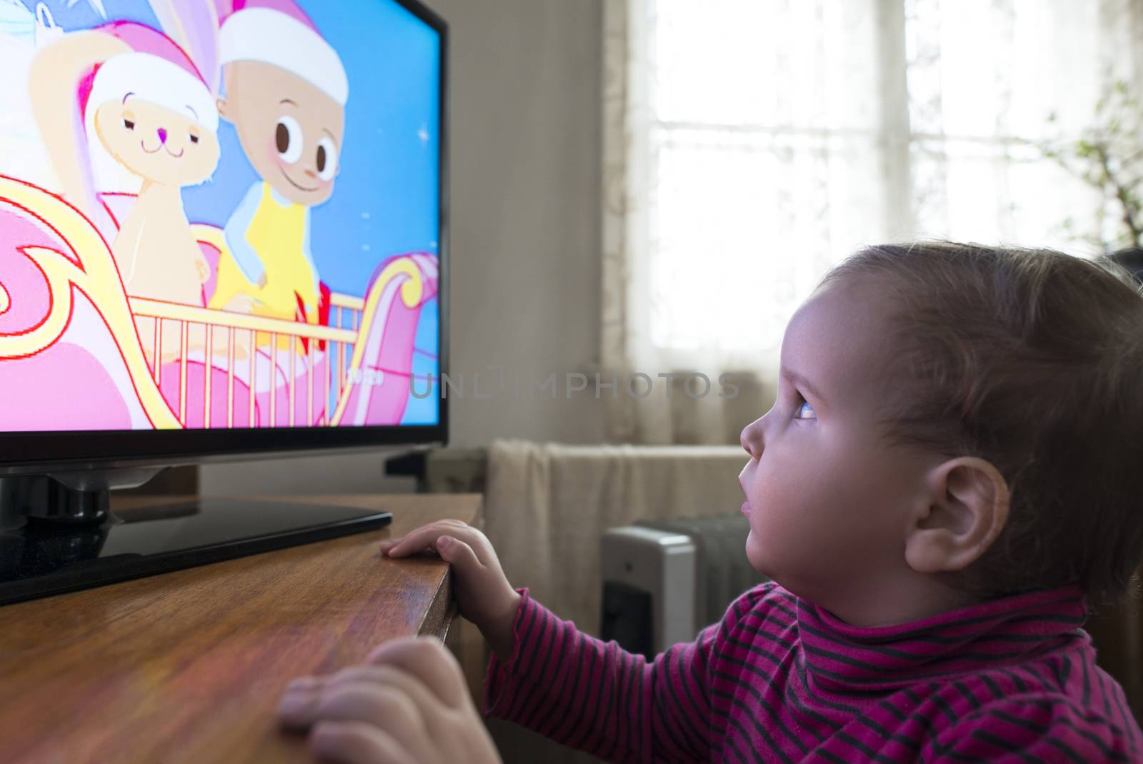 Baby girl watch TV. In fron of the TV.